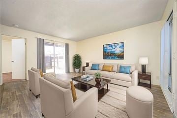 Hemet apartment for rent - A living room with a white couch, a coffee table, and a painting on the wall.