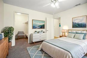 Hemet multi-family for rent - A bedroom with a bed, dresser, chair, and painting.