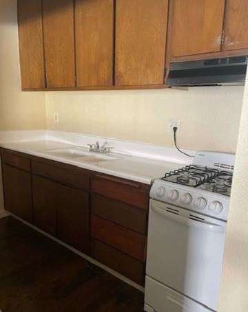 Covina multi-family for rent - A white gas stove is in a kitchen with wooden cabinets.