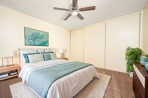 Hemet apartment for rent - A bedroom with a bed, a ceiling fan, and a painting on the wall.
