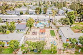 Moreno Valley apartment for rent - A large white building with a pool in the middle of a grassy area.