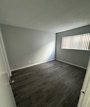 Pomona apartment for rent - A room with wooden flooring and a window with blinds.