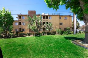 Sylmar multi-family for rent - A brown building with a green lawn in front.