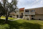 Hemet multi-family for rent - A building with a red roof and a tree in front of it.