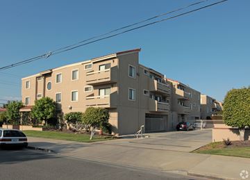 Gardena multi-family for rent - A beige apartment building with a car parked in front.