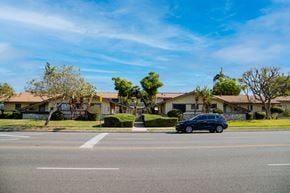 Covina multi-family for rent - A tan building behind trees
