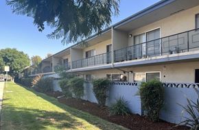 Claremont multi-family for rent - A row of houses with balconies and a green lawn in front.