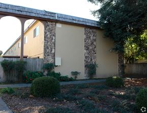 Cotati multi-family for rent - A house with a stone wall and a wooden fence.