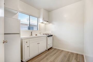 Sylmar multi-family for rent - A small kitchen with white cabinets and a window.