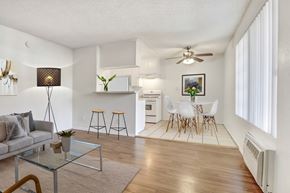 Sylmar multi-family for rent - A living room with a grey sofa, a glass coffee table, and a bar area with stools.