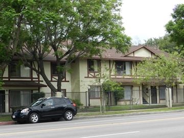 Ontario multi-family for rent - A black car is parked on the side of a street in front of a two-story house.
