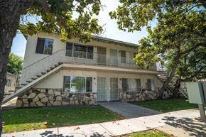 La Puente multi-family for rent - A house with a stone wall and a tree in front.