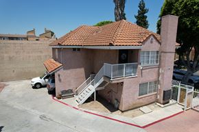 Paramount multi-family for rent - A house with a red tile roof and a white car parked in front.