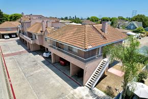 Paramount multi-family for rent - A large house with a red tiled roof and a white car parked in front.