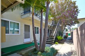 Downey multi-family for rent - A house with a green lawn and a tree in front.