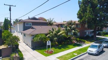 Downey multi-family for rent - A residential street with houses and parked cars.
