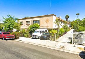 Los Angeles multi-family for rent - A red pickup truck is parked on the side of a street in front of a house.