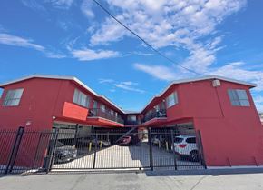 Lynwood multi-family for rent - A red building with a black gate and cars parked in front.