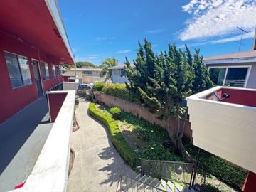 Lynwood multi-family for rent - A red building with a balcony overlooking a green garden.