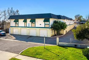 Upland multi-family for rent - A building with a green roof and white walls with a blue sign on it.