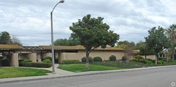 Claremont multi-family for rent - A tree in front of a building with a street light to the left.