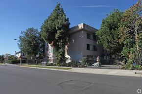 Los Angeles multi-family for rent - A modern building with a grey facade is surrounded by trees and a clear blue sky.