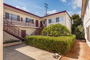 Torrance multi-family for rent - A white house with a red roof and a brown hedge in front.