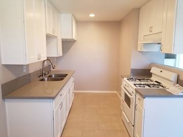 Long Beach multi-family for rent - A kitchen with white cabinets and a stove top oven.