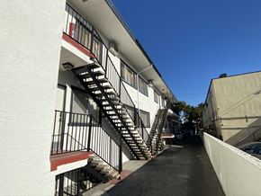 Los Angeles multi-family for rent - A long white building with a red stripe and a black metal staircase.