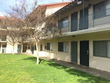 Montebello multi-family for rent - A tree in front of a building with a green door.