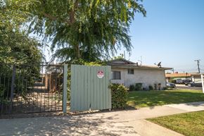 La Puente multi-family for rent - A white house with a red and white sign on a gate.
