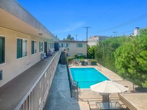 Monrovia multi-family for rent - A pool with a sun lounger and umbrella is surrounded by a fence.