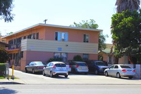 Huntington Park multi-family for rent - A building with a pink and yellow facade has cars parked in front.