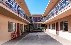 Los Angeles multi-family for rent - A balcony with a red table and chairs is on the left side of a building.