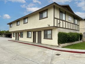 Fontana multi-family for rent - A two-story building with a beige and brown exterior and a red line on the sidewalk.