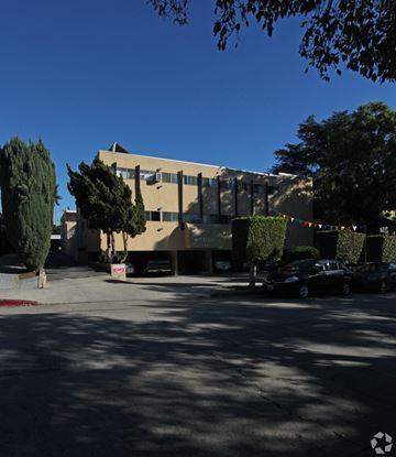 Los Feliz multi-family for rent - A building with a yellow facade and a sign that says "Taliesin" is surrounded by trees and has cars parked in front.