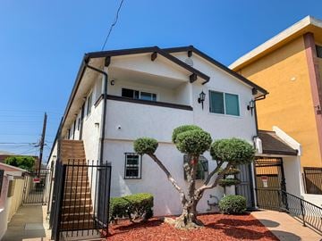 Hawthorne apartment for rent - A white house with a black gate and two small trees in front.