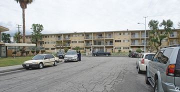 Covina multi-family for rent - A parking lot with cars and apartment buildings in the background.
