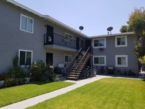 Northridge multi-family for rent - A grey two-story apartment building with a balcony and stairs leading to the second floor.