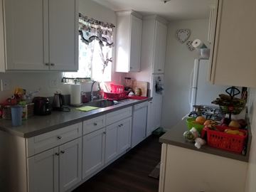 Northridge multi-family for rent - A kitchen with white cabinets and a counter with a basket of fruit on it.
