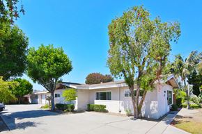 Downey multi-family for rent - A white house with a tree in front of it.