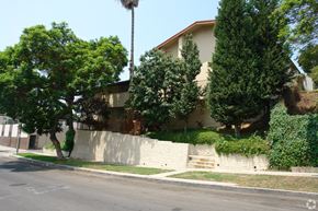 Los Angeles multi-family for rent - A house with a white fence and trees in front.