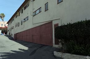 Los Angeles multi-family for rent - A building with a red garage door and a tree in front.
