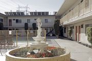 Bellflower multi-family for rent - A white statue of a woman stands in the middle of a garden.