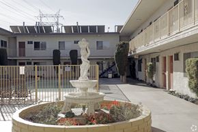 Bellflower multi-family for rent - A white statue of a woman stands in the middle of a garden.