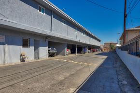 El Monte multi-family for rent - A parking lot with a building on the left and a car parked in the garage.