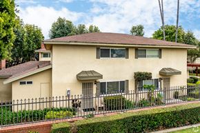 Claremont multi-family for rent - A house with a brown roof and a black fence.