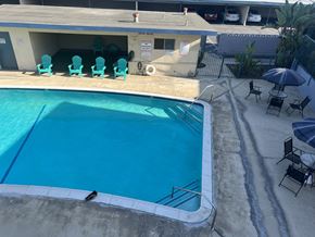Claremont multi-family for rent - A pool with a diving board and chairs around it.