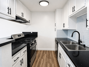 Gardena multi-family for rent - A kitchen with black countertops and white cabinets.