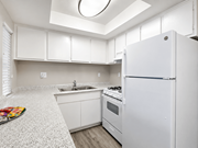 Hemet multi-family for rent - A white kitchen with a refrigerator, sink, and stove.